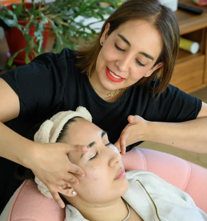 Les mains de Selene posées sur les tempes d’une cliente qui sourit, les yeux fermés