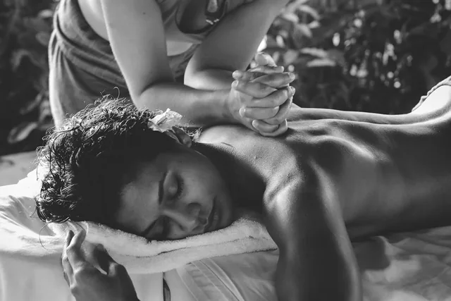En noir et blanc, un massage du dos, la personne allongée sur la table, les yeux fermés